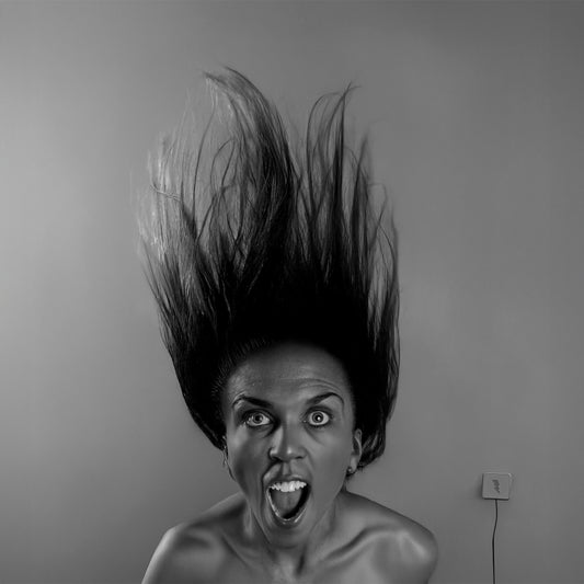 A Big Fan by Erin Naifeh - dramatic black and white photography of figure with hair blown by fan powered by high-voltage electrical outlet